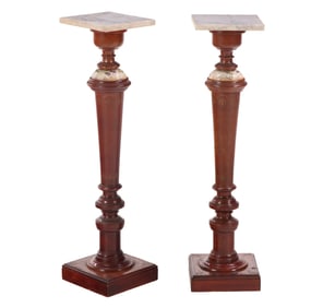 A PAIR OF MATCHING TURNED AND CARVED WALNUT PEDESTALS HAVING MARBLE TOPS AND ENAMELED COLLARS