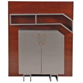 AN ART DECO PAINTED TWO DOOR CABINET WITH ANGULAR BOOKSHELF MOUNTED ON A MAHOGANY WALL PANEL.
