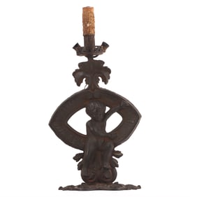 A LARGE IRON LAMP IN THE FORM OF A PUTTI.