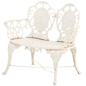 A TWO SEAT CAST IRON GARDEN BENCH WITH ARMS.