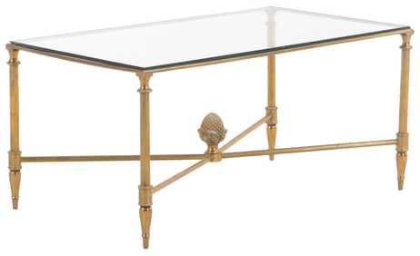 A BRASS AND GLASS COFFEE TABLE HAVING AN X STRETCHER BASE SUPPORTING A LARGE ACORN FINIAL AND