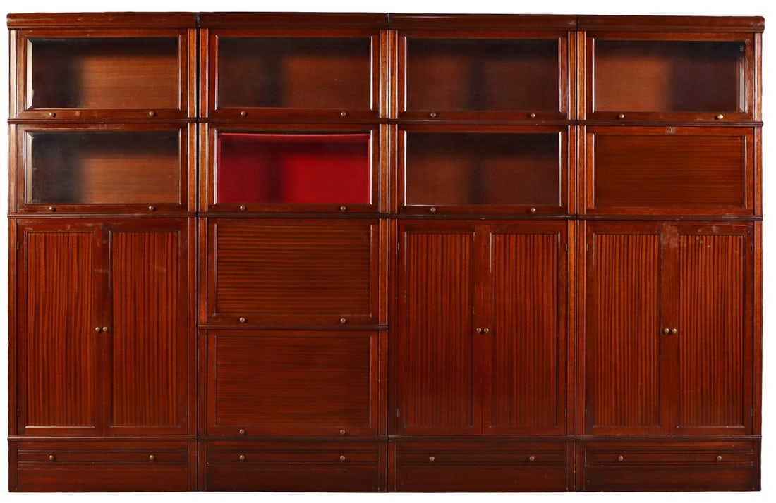 A LARGE RIBBON MAHOGANY STACKING BARRISTER BOOKCASE HAVING BEVELED GLASS, A MIRRORED BAR: A large ribbon mahogany stacking barrister bookcase having beveled glass, a mirrored bar compartment and drawers in the base C 1940. Ht: 80" Wd: 126.5" Dpth: 15.25"
