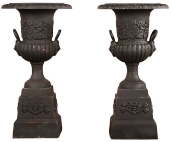 A PAIR OF PAINTED CAST IRON CAMPAGNA FORM GARDEN URNS WITH HANDLES RESTING ON SEPARATE CAST IRON