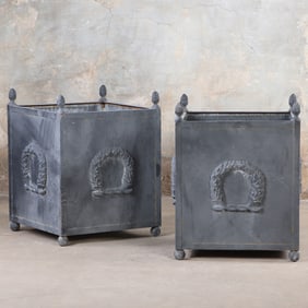 A PAIR OF REGENCY STYLE IRON PLANTER BOXES HAVING WREATH DECORATION AND RESTING ON BALL FEET.
