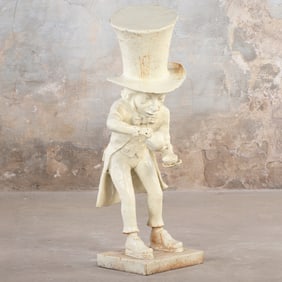 A PAINTED CAST IRON GARDEN SCULPTURE DEPICTING THE MAD HATTER POURING A CUP OF TEA.