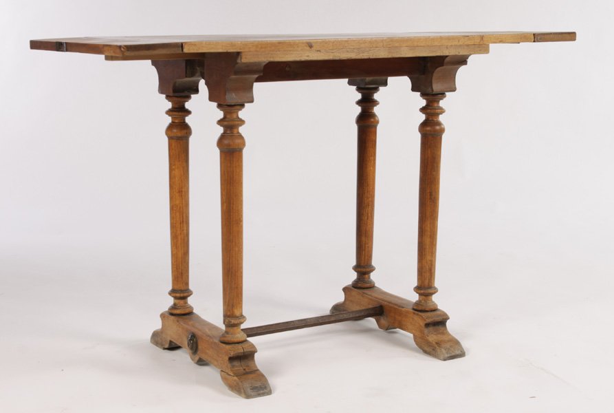 CONTINENTAL WALNUT DROP SIDE WORK TABLE: A Continental walnut drop side small work table having turned legs and a trestle base with iron stretcher circa 1920. Drops measure 4.5" Ht: 28.5" Width: 33.5" Depth: 21.5"