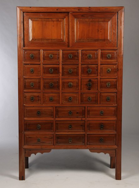 CHINESE APOTHECARY CABINET 29 DRAWERS: A Chinese apothecary cabinet having two raised paneled sliding doors over twenty-nine smaller drawers. Ht: 71" Width: 43" Depth: 16.5"