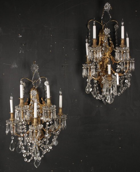 PR LARGE CALDWELL BRONZE CRYSTAL SCONCES 5 ARMS: A pair of large Caldwell style bronze and crystal sconces, each having ornate backplates supporting five acanthus leaf decorated arms. The arms with glass bobeches, draped garland, and faceted drop cr