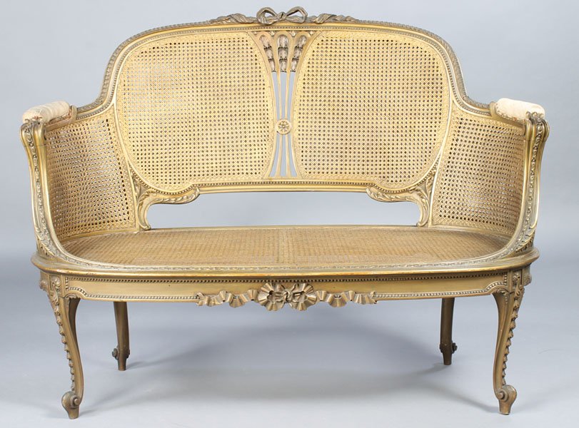 LOUIS XV STYLE DOUBLE CANED SETTEE SHAPED ARMS: A Louis XV style double caned back settee having central bow cartouche over paneled back and shaped arms with scroll decoration circa 1900. Ht: 41" Width: 52" Depth: 24"