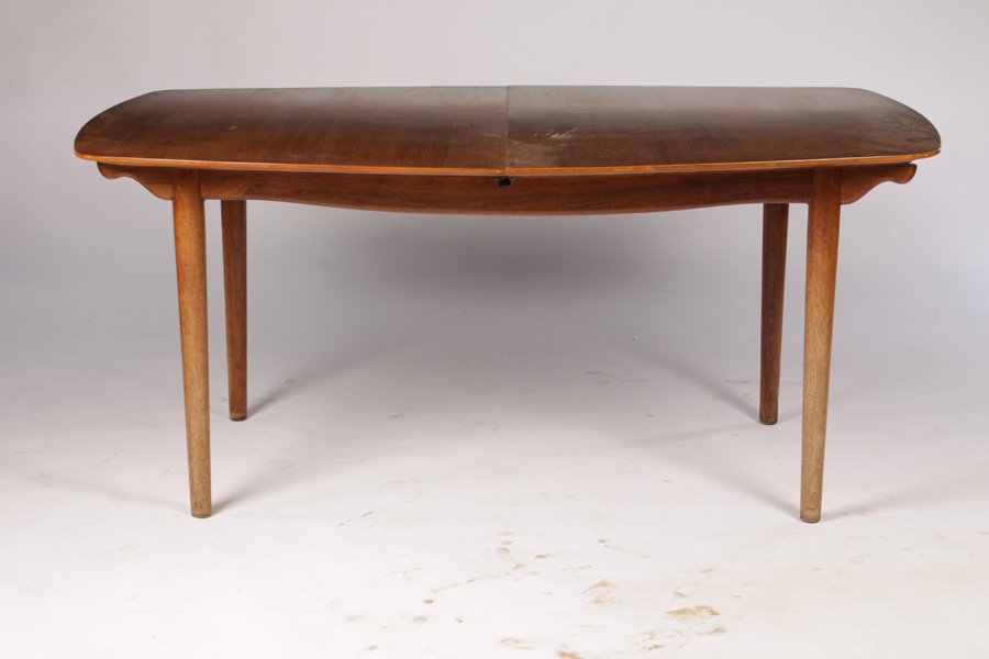 LABELED BAKER DINING TABLE MODERN 2 LEAVES: A labeled Baker dining table in the modern taste having a shaped top supported on turned and tapered legs. Having two leaves measuring 15" each. Ht: 29.5" Width: 67" Depth: 47"