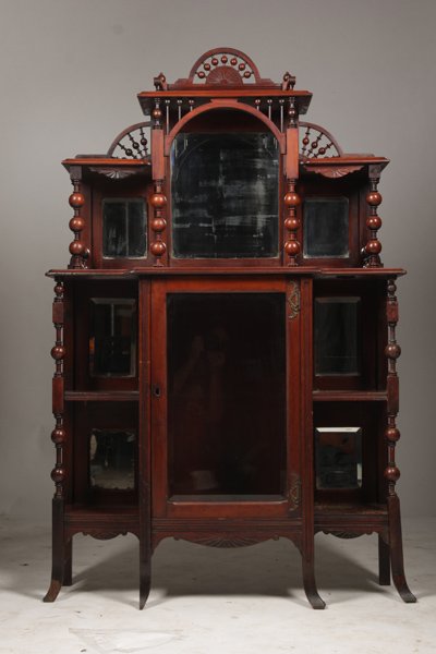 AMERICAN VICTORIAN CARVED MAHOGANY ETEGERE: American Victorian carved mahogany etegere with stick and ball decorated upper open shelves over central glass front cabinet circa 1890. Ht: 66" Width: 42" Depth: 14.5"