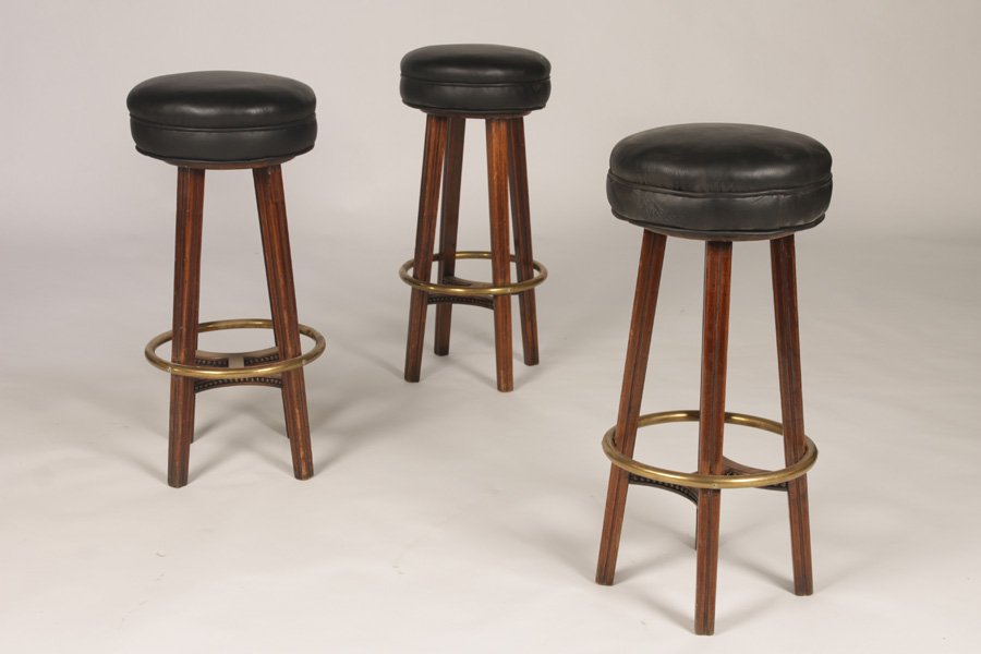 SET OF 3 BAR STOOLS WITH UPHOLSTERED SEATS: A set of three bar stools having upholstered seats supported on four splayed legs with brass foot rest and decoration stretcher. Ht: 29"