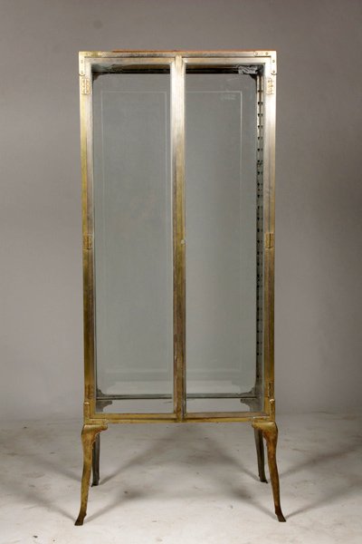 NEOCLASSICAL BRONZE 2-DOOR VITRINE CIRCA 1920: A Neoclassical bronze two door vitrine having glass front, back, and sides supported on shaped legs with stylized hoof feet circa 1920. Ht: 67" Width: 28" Depth: 16"