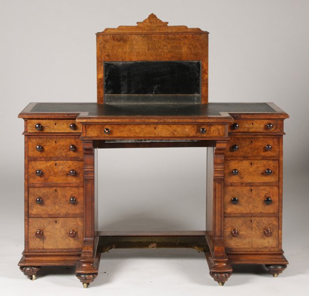 ENGLISH EDWARDIAN BURL WOOD DESK: An English Edwardian burl wood desk having drop down mirror and inset canvas top circa 1870. The central drawer flanked by two sets of five drawers, raised on carved feet. Ht: 29" Width: 48" Depth: 21