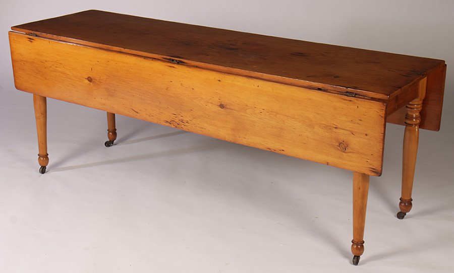 19TH CENT. DROP LEAF DINING TABLE: American nineteenth century drop leaf dining table supported on turned legs and casters. Ht: 27.5" Width: 72" Depth: 21"