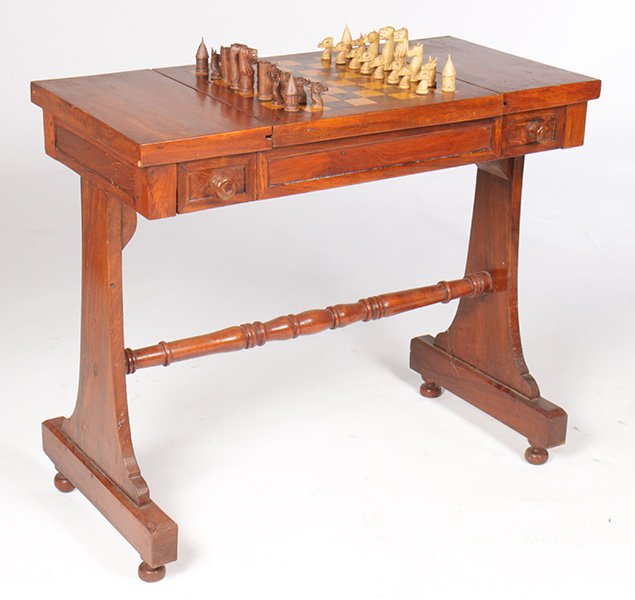 CARVED GAMES TABLE W/CHESS & CHECKER PIECES: A carved games table having central game board over two drawers with carved chess pieces and checkers. Ht: 31" Width: 35" Depth: 18"