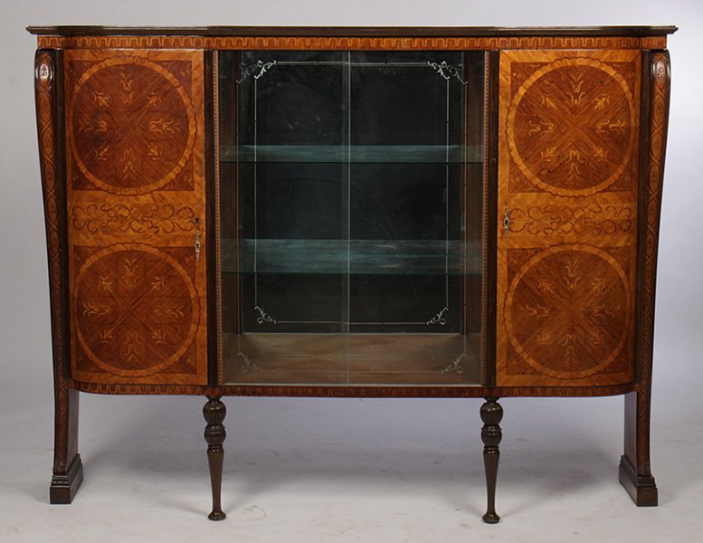 ITALIAN INLAID BOOKCASE MIRRORED BACK OPEN SHELVE: An Italian inlaid bookcase having stepped cornice over central mirrored back open shelves circa 1920. The shelves flanked by two marquetry inlaid chevron and banded curved doors, supported by side bra