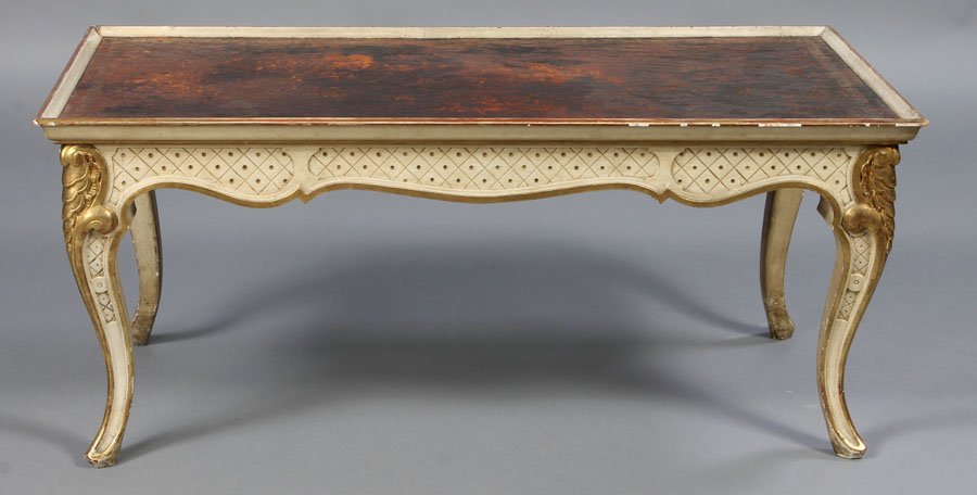 LEATHER TOP PAINTED GILTWOOD COFFEE TABLE JANSEN: A Jansen coffee table having a leather top over shaped and incised apron supported on giltwood carved cabriole legs circa 1960. Ht: 18" Width: 41.5" Depth: 21.5"