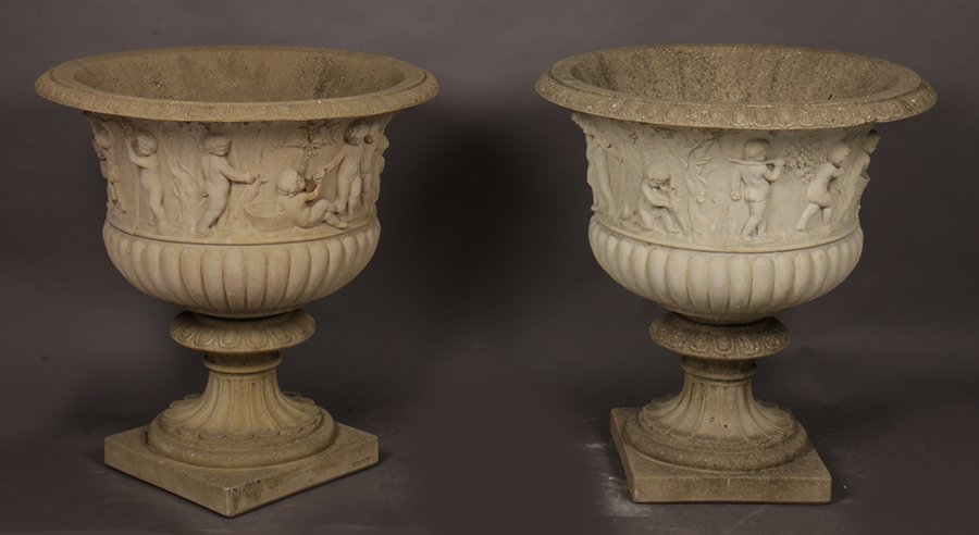 LARGE PR CAST STONE GARDEN URNS BACCHANALIAN: A large pair of cast stone garden urns having egg and dart rim over figural bacchanalian wine celebration. Having a lobed bowl, raised on fluted base. Ht: 33" Dia: 30"