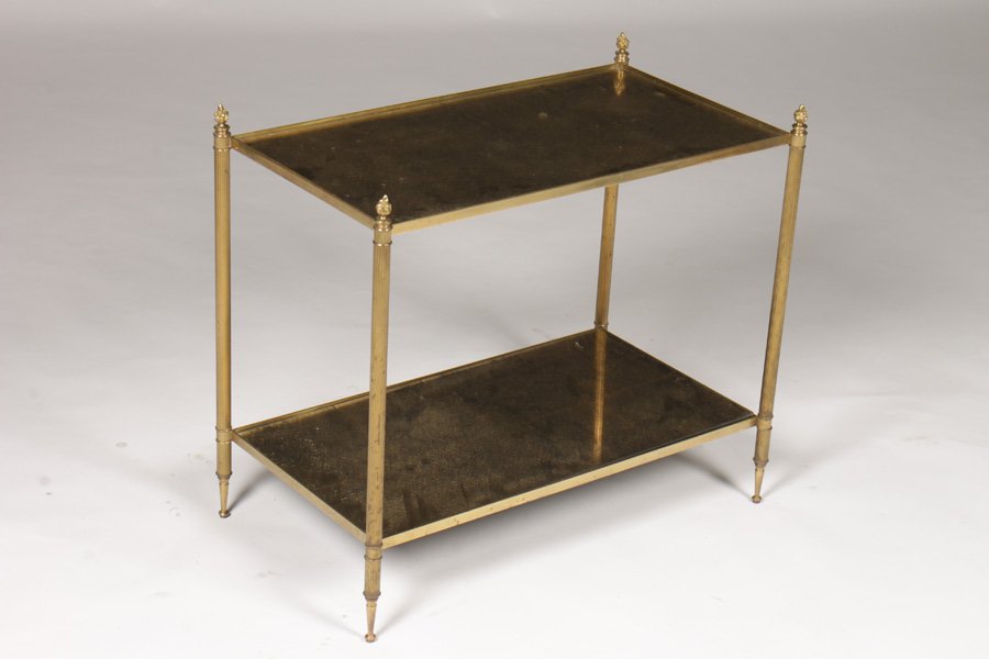 JANSEN BRONZE GOLD GLASS 2-TIER OCCASIONAL TABLE C.1940: A Jansen two tier bronze and gold glass occasional table with flame finials and resting on tapered feet circa 1940. Dimensions: Ht: 24" Width: 27" Depth: 15"