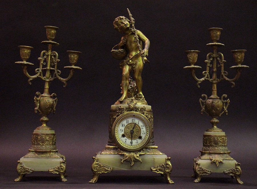 3 PC METAL & ONYX GARNITURE CLOCK SET 1880: A three piece onyx and white metal garniture clock set having a young boy holding a walking stick and fruit basket circa 1880. The clock flanked by urn themed candelabrum. Ht: 9" Width: 8" Depth: 7"