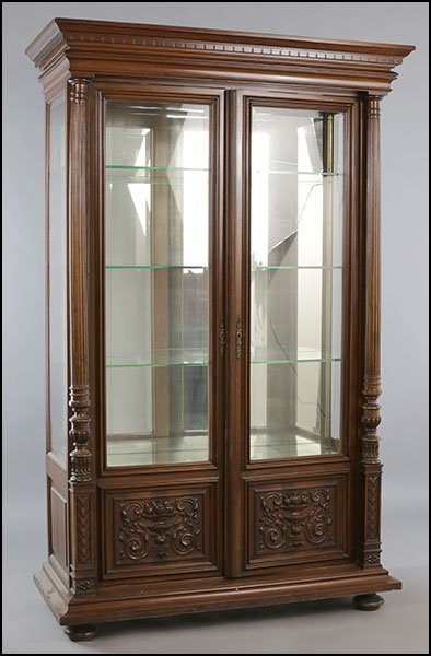 CARVED WALNUT CABINET CORNUCOPIA CIRCA 1900: A Continental carved walnut cabinet having column form with scroll and cornucopia motifs beneath the two-doors and a mirrored back circa 1900. Having interior glass shelves. Dimensions: Ht: 78.5" Widt