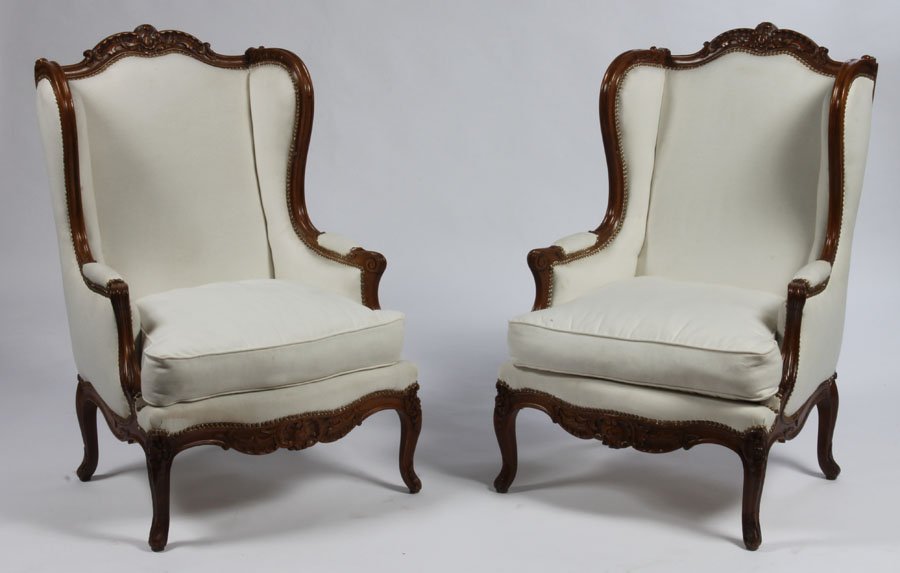PR WINGED BACK BERGERE CHAIRS CARVED: A pair of Louis XVI style winged back bergere chairs having carved and shaped crest over downswept arms and loose cushion seat circa 1920. Raised on cabriole legs. Dimensions: Ht: 45" Width: 29.5" Dep