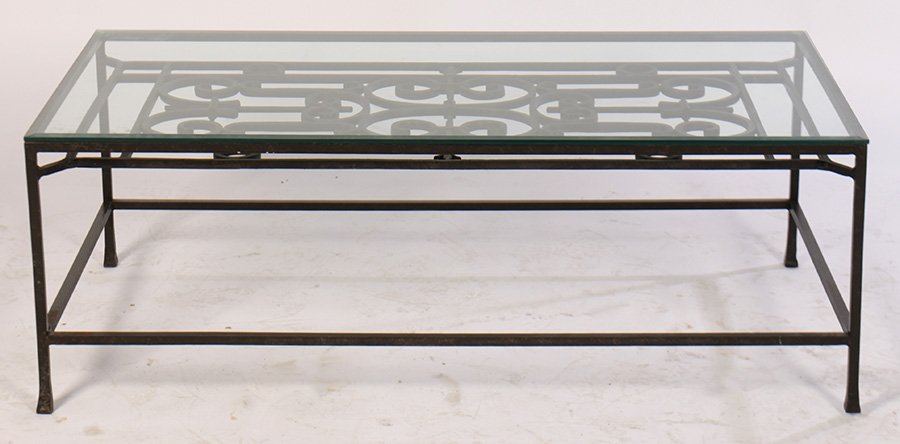 WROUGHT IRON COFFEE TABLE WITH GLASS TOP: A wrought iron coffee table having glass top over scroll decorated panel. Ht: 17" Width: 49.5" Depth: 25.5"