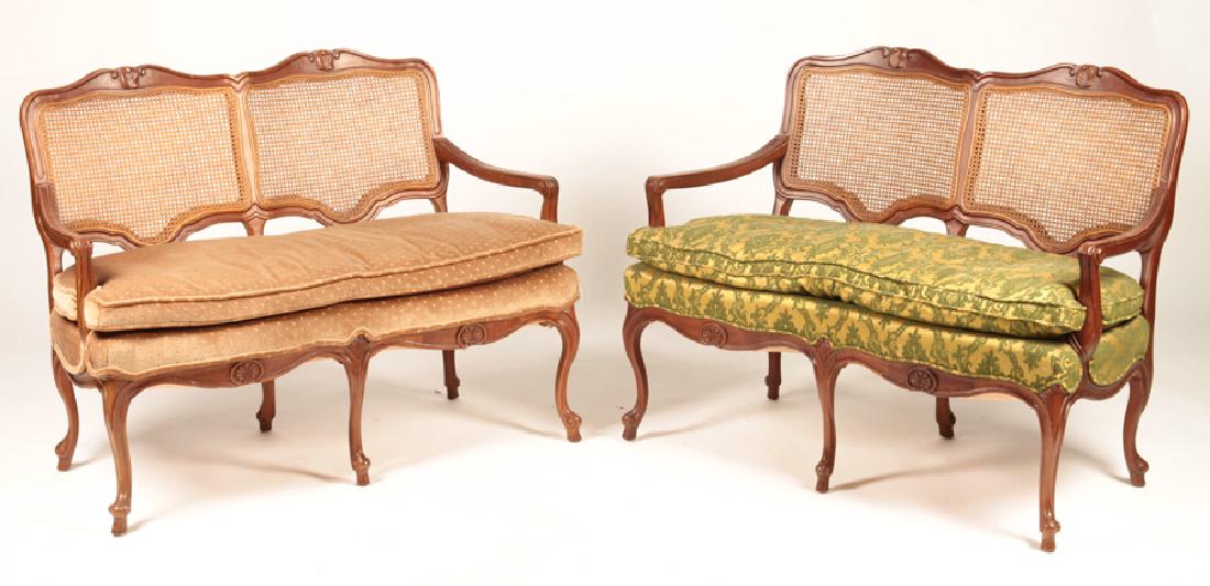 PAIR LOUIS XV STYLE SETTEES LOOSE CUSHION SEATS: A pair of Louis XV style settees, each having caned backs over open arms and loose cushion seats supported on cabriole legs. Ht: 33.5" Wd: 43" Dpth: 19"