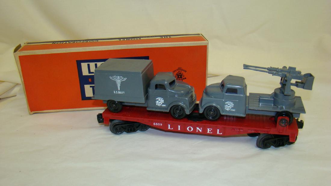 LIONEL 6809 FLAT CAR WITH MILITARY UNITS - NIB: LIOENL 6809 FLAT CAR WITH MILITARY UNITS - NIB - USMC ANTI AIRCRAFT TRUCK & USMC TRUCK CARRYING US NAVY MEDICAL - APPEARS COMPLETE - BOX DISCOLORATION