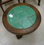 ROUND WOODEN AND GREEN TILE END TABLE: ROUND WOODEN AND GREEN TILE END TABLE - UNDER SHELF AND 4 HIGHLY CARVED WOODEN LEGS - 17'' X 24'' - SHOWS WEAR ON THE WOOD - ONE SMALL CHIP IN TILE AND GROUT IS AGED