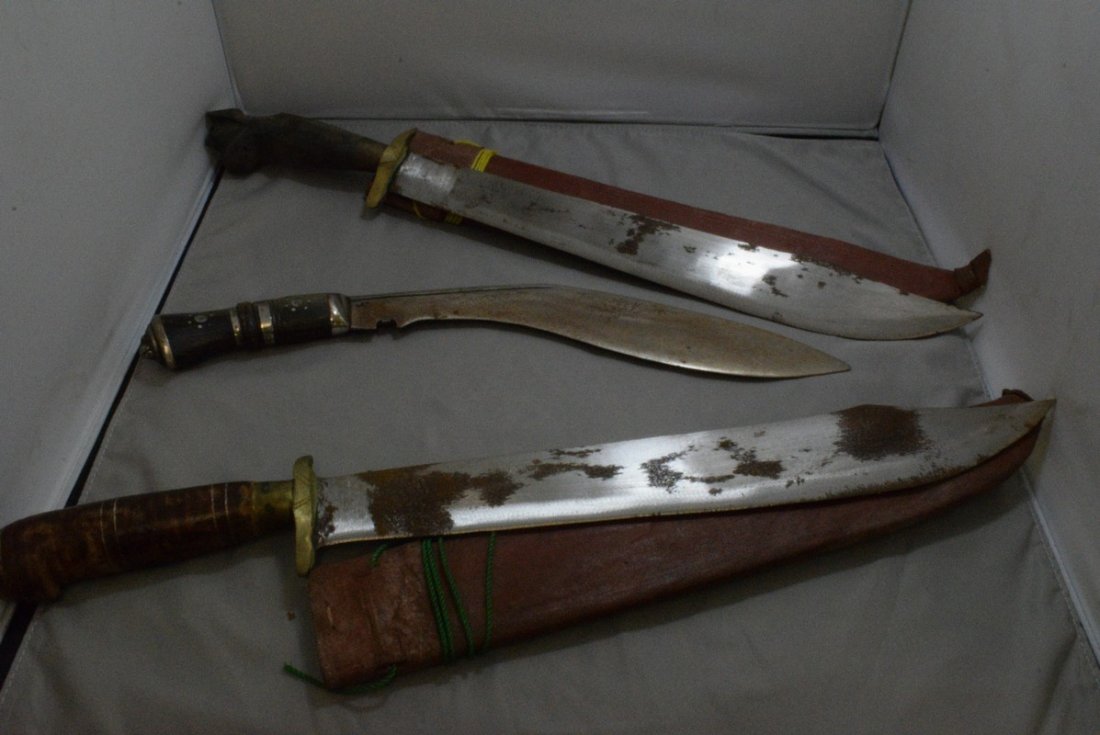 3 DECORATIVE ARABIAN STYLE MACHETES AND A DECORATIVE: 2 DECORATIVE ARABIAN STYLE MACHETES WITH LEATHER SHEATHS - 1 WRAPPED HANDLE AND 1 CARVED WOOD HANDLE A DECORATIVE LONG KNIFE - NO SHEATH - LOOKS LIKE SEVERAL WORM HOLES ON HANDLE - BLADES HAVE SOME RU