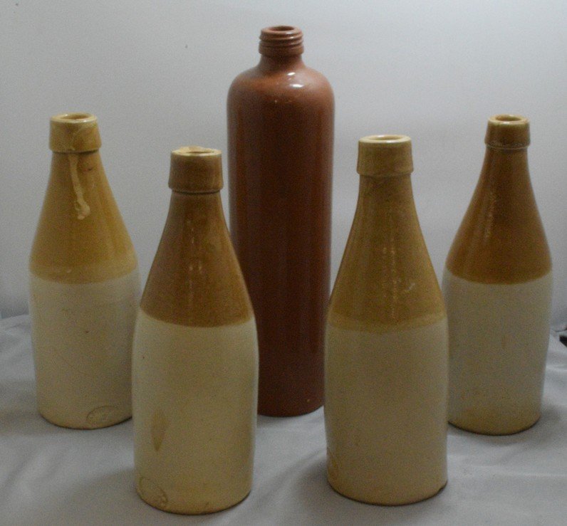 4 VINTAGE CROCK GINGER BEER BOTTLES AND A POTTERY: 4 VINTAGE CROCK GINGER BEER BOTTLES - ALL HAVE CHIPS ON THE BOTTOM AND A VINTAGE 11 BROWN POTTERY WINE BOTTLE