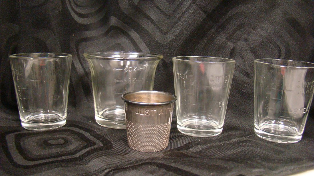 VINTAGE ALCOHOL MEASURING GLASSES/CUPS: VINTAGE ALCOHOL MEASURING GLASSES/CUPS - 5 ITEMS TOTAL - 1 BETTY TAPLIN 4 OZ., (3) 4 TABLE SPOONS/8 TEASPOON MEASUREMENT - EMBOSSSED FOR MEASURING WINE AND TEA AND 1 METAL SHOT GLASS - ''JUST A THIMBL