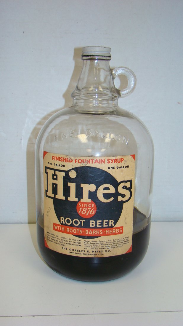 VINTAGKE 1 GAL JUG HIRES ROOT BEER SYRUP BOTTLE: VINTAGE 1 GALLON GLASS ''HIRES'' ROOT BEER SYRUP - WHITE LABEL WITH BLUE AND RED PRINT - METAL SCREW OFF TOP - PARTIALLY FILLED - BUYER RESPONSIBLE FOR MAKING SHIPPING ARRANGEMENTS