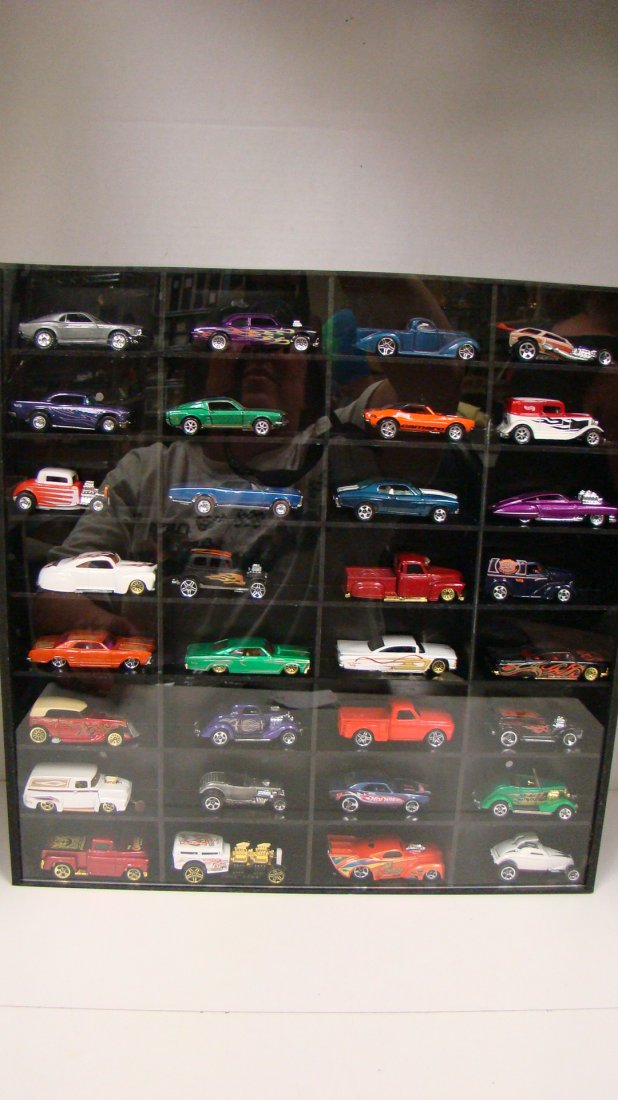 32 VARIOUS HOT WHEELS CARS IN DISPLAY: 32 VARIOUS HOT WHEELS DIE-CAST CARS - BLACK AND CLEAR PLASTIC DISPLAY - TOP OF DISPLAY IS DENTED
