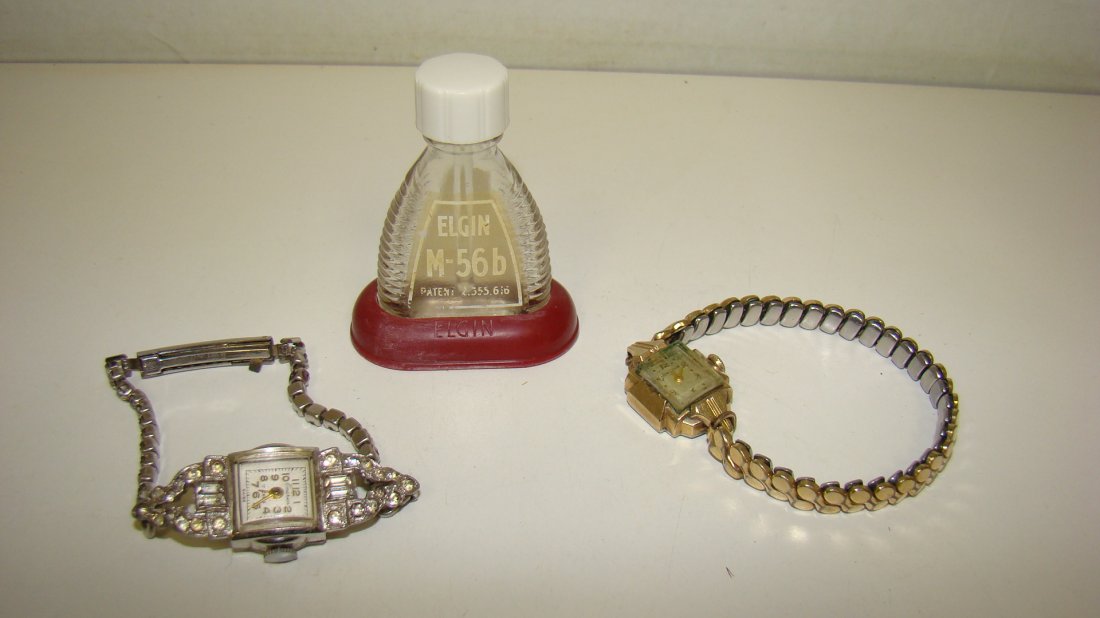 2 VINTAGE LADIES WATCHES-1 BULOVA & 1 EMERSON: 2 VINTAGE LADIES WRISTWATCHES - FANCY EMERSON 17 JEWEL - RHINESTONE BAND AND A VINTAGE BULOVA - GOLD TONE STRETCH BAND - CRYSTAL IS VERY SCRATCHED AND SMALL EMPTY ELGIN M-56b OIL BOTTLE