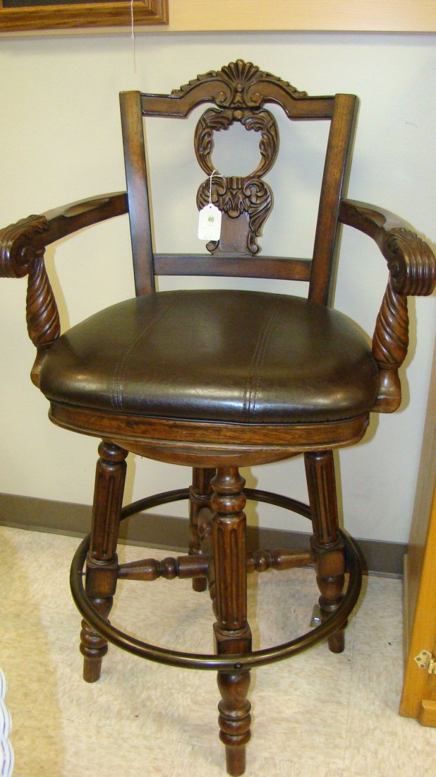 FANCY CARVED BACK SWIVEL BAR STOOL: FANCY CARVED BACK SWIVEL BAR STOOL - CARVED ARMS AND BACK - LEATHER SEAT - METAL SUPPORT AROUND LEGS - VERY STURDY - VERY NICE PIECE - 45'' TALL - BUYER RESPONSIBLE FOR MAKING SHIPPING ARRANGEMENTS