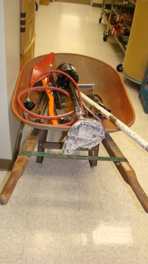 WHEEL BARROW W/ CONTENTS: WHEEL BARROW WITH CONTENTS - FLOOR JACK HANDLE - SUBMERCIBLE PUMP - WAYNE DRILL PUMP AND MORE - BUYER RESPONSIBLE FOR MAKING SHIPPING ARRANGEMENTS