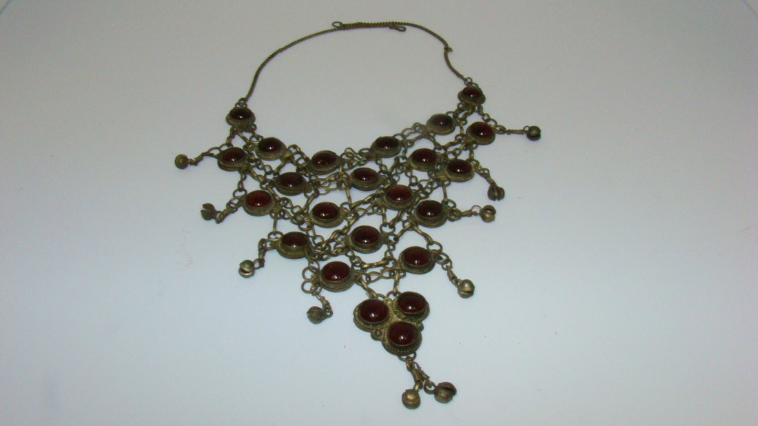UNIQUE VINTAGE COSTUME NECKLACE: UNIQUE VINTAGE BRASS AND RED STONE CHOKER - STARTS WITH 6 RED STONES ACROSS AT TOP AND NARROWS DOWN TO 1 RED STONE - HANGS DOWN APPROX 8'' - NO MARKS