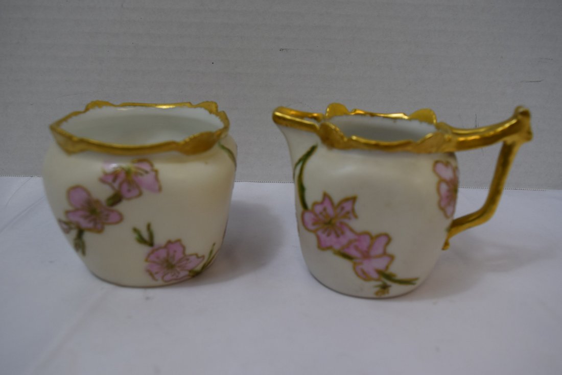 ANTIQUE T & V LIMOGES SUGAR AND CREAMER SET: ANTIQUE T & V LIMOGES SUGAR AND CREAMER SET. CREAM COLORED BACKGROUND WITH PINK FLOWERS AND GREEN VINES. GOLD ACCENTS AROUND RIMS, HANDLES AND FLOWERS. EXCELLENT CONDITION