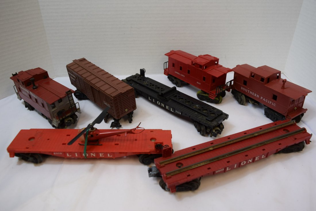 7 PIECE BOX LOT OF LIONEL AND OTHER ROLLING TRAIN: 7 PIECE BOX LOT OF LIONEL AND OTHER ROLLING TRAIN CARS. 6819 RED FLAT CAR WITH RED HELICOPTER - DAMAGED WINDOW ON HELICOPTER, 6805 FLAT CAR WITH METAL RAILS FOR RADIO ACTIVE WASTE- NO RADIO ACTIVE WAS