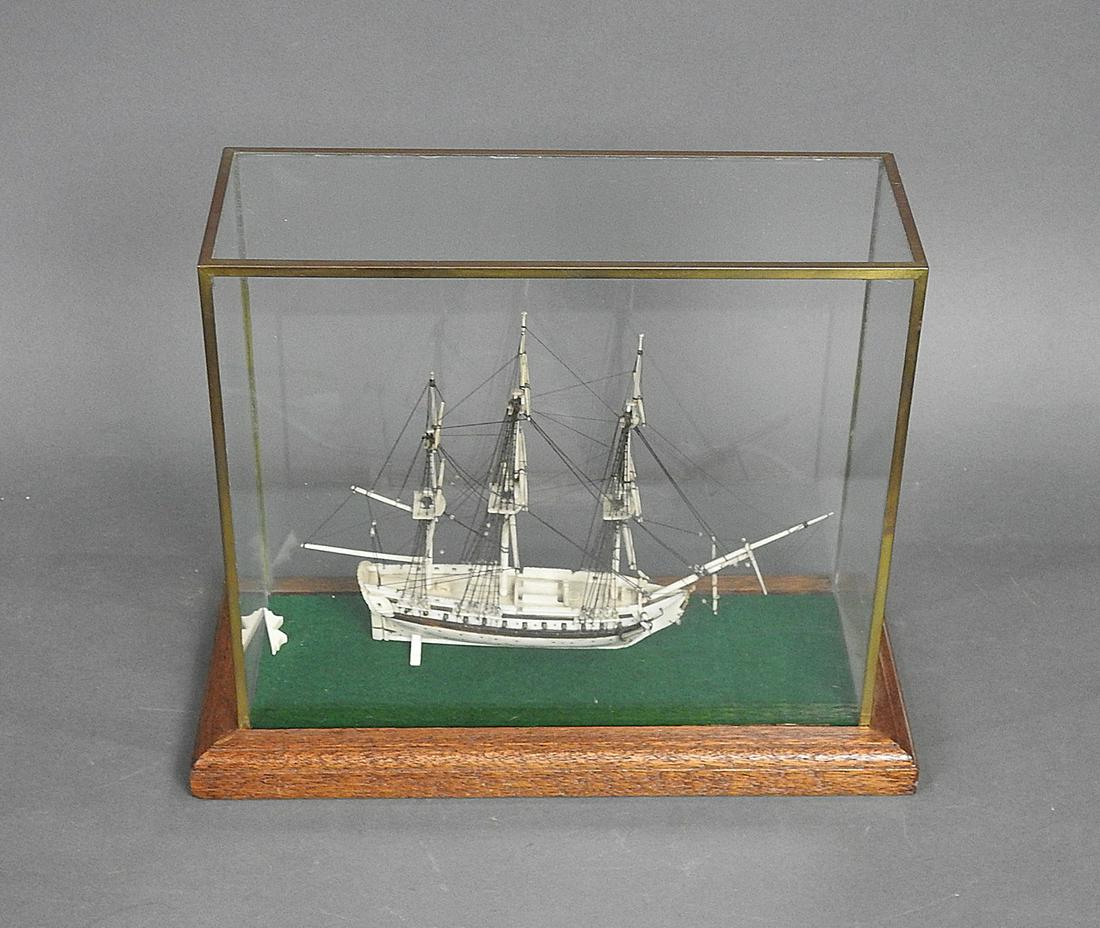 BONE SHIP INSIDE DISPLAY CASE: Glass top case. Wooden base. Bone ship. 9 7/8" h x 12 1/8" w x 5 1/2" d.