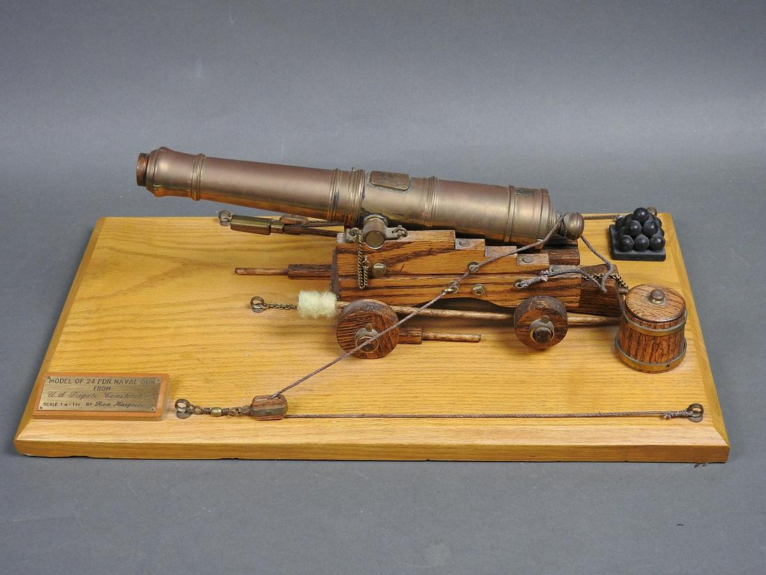 MINITURE NAVEL GUN FROM U.S FRIGATE CONSTITUTION BY RON: Brass and oak cannon on oak base. Including accessories, cannon balls, and lidded barrel. 5 1/8" h x 5" w x 11 3/4" d. scale 1 inch to 1 ft.