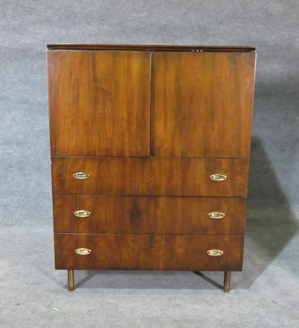 JOHN STUART HIGH CHEST BERT ENGLAND DESIGN: Signed. Wood. 2 doors on top containing 4 drawers on one side and 1 shelf on the other side. 3 drawers on bottom. Metal hardware. 49" h x 37" w x 20" d.