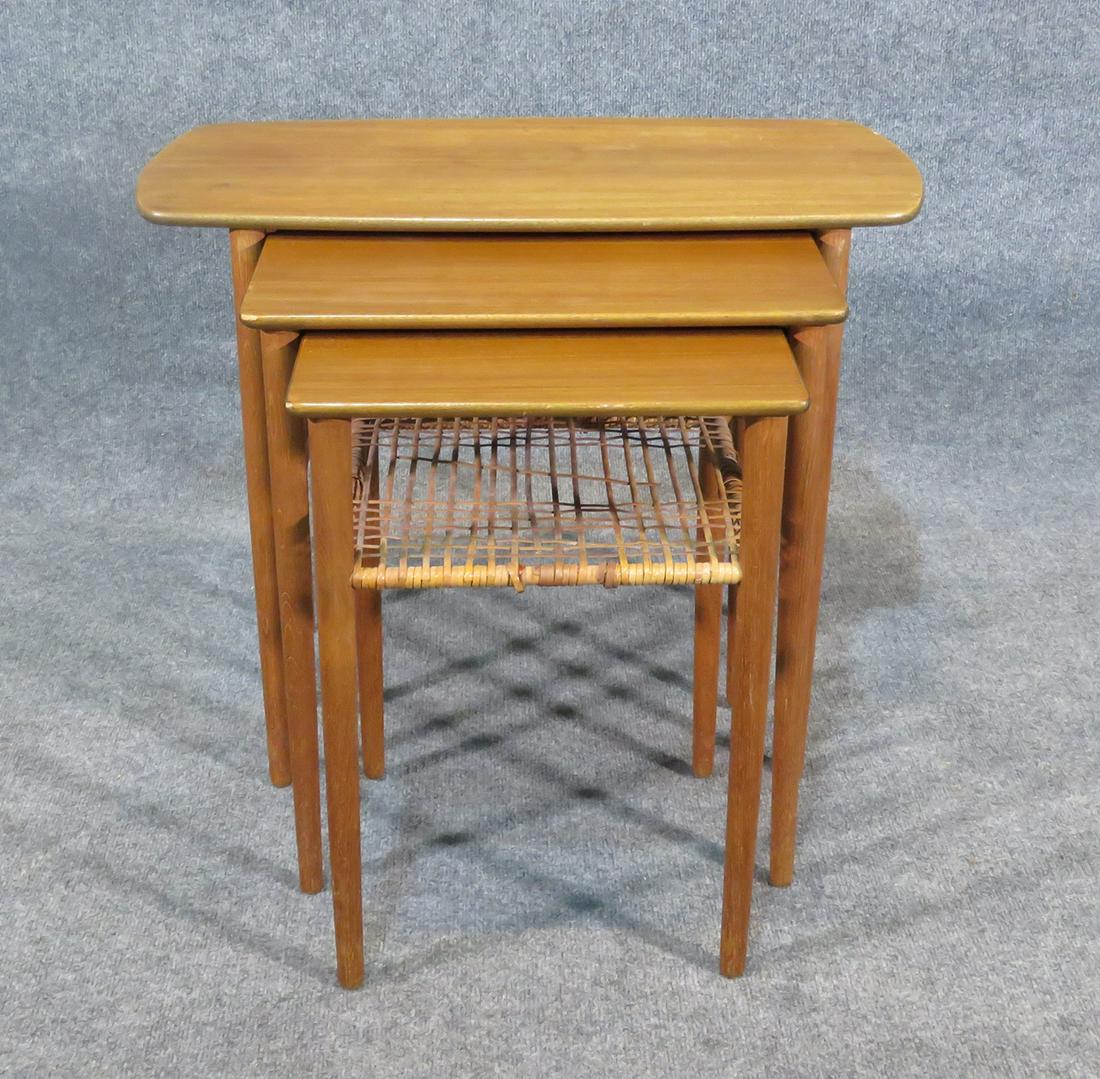 3 PC TEAK DANISH NEST OF TABLES: Cane bottom. Teak. 21 1/4" h x 26 1/2" w x 14 1/2" d.