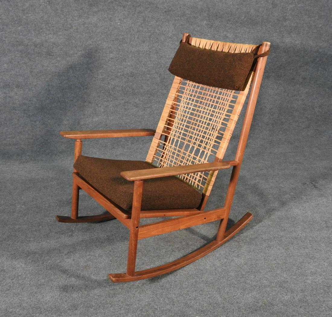 J K DANISH ROCKER: Teak frame. Made in Demark. Danish control label. Woven reed back. 38 1/4" h x 25 7/8" w x 36" d. Seat height 19".