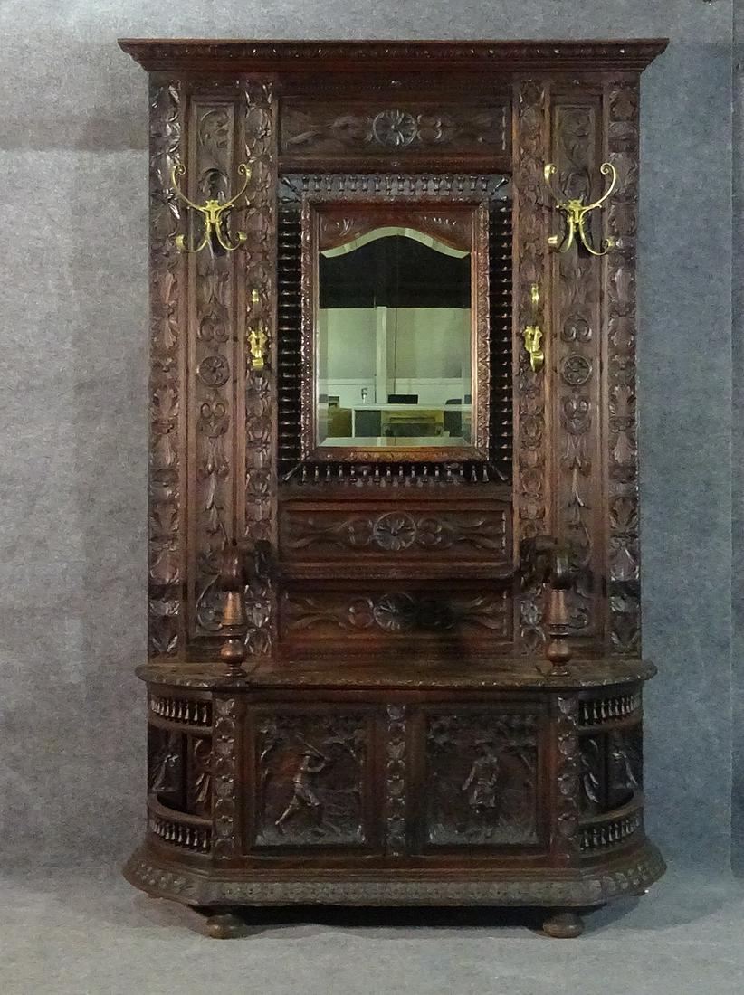 ANTIQUE CARVED HALL RACK: With built in bench. Carved. Walnut. Metal hardware. Beveled glass mirror.