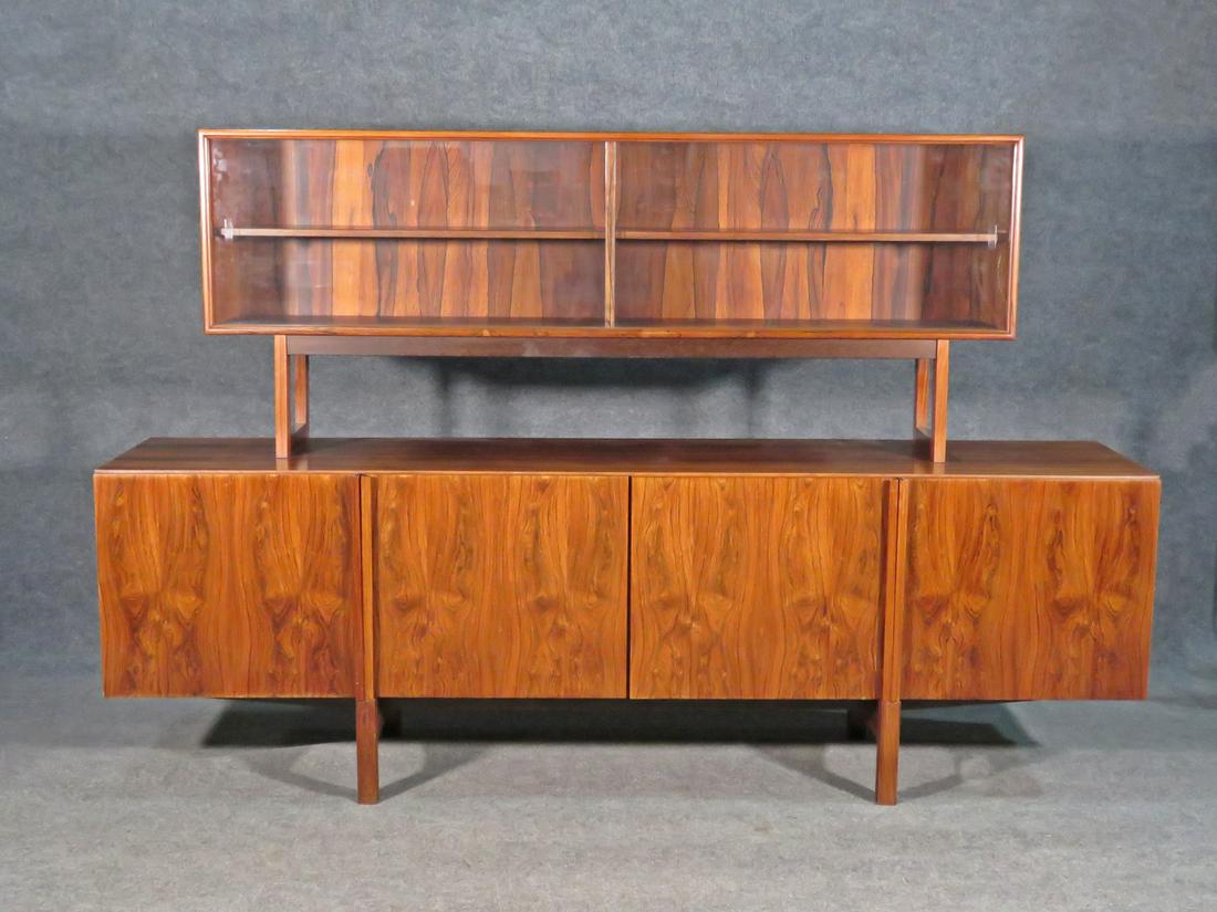 KOFOD LARSEN CREDENZA: Made in Demark. 2 piece. Top has 2 glass sliding doors containing one shelf. Bottom has four doors. Left doors has 4 dovetailed drawers. Bottom piece measures 29" h x 90 1/2" w x 20 1/2" d. Top piece 