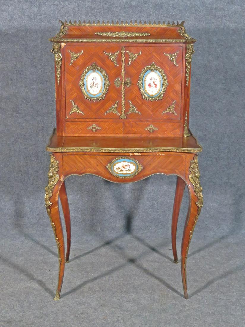 LOUIS XV STYLE LADIES DESK: Porcelain inserts. 3 pc. Brass accents and hardware. Gallery top. 2 doors containing shelves. 2 dovetailed drawers. 48 1/4" h x 26 3/4" w x 19" d.